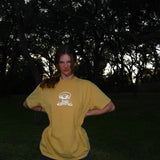 Person wearing a yellow t-shirt with a logo in a dark outdoor setting