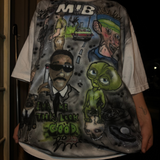 T-shirt with graphic design featuring characters and text, held by a person.