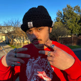 Person wearing a red sweatshirt with a graphic design, making a peace sign outdoors.