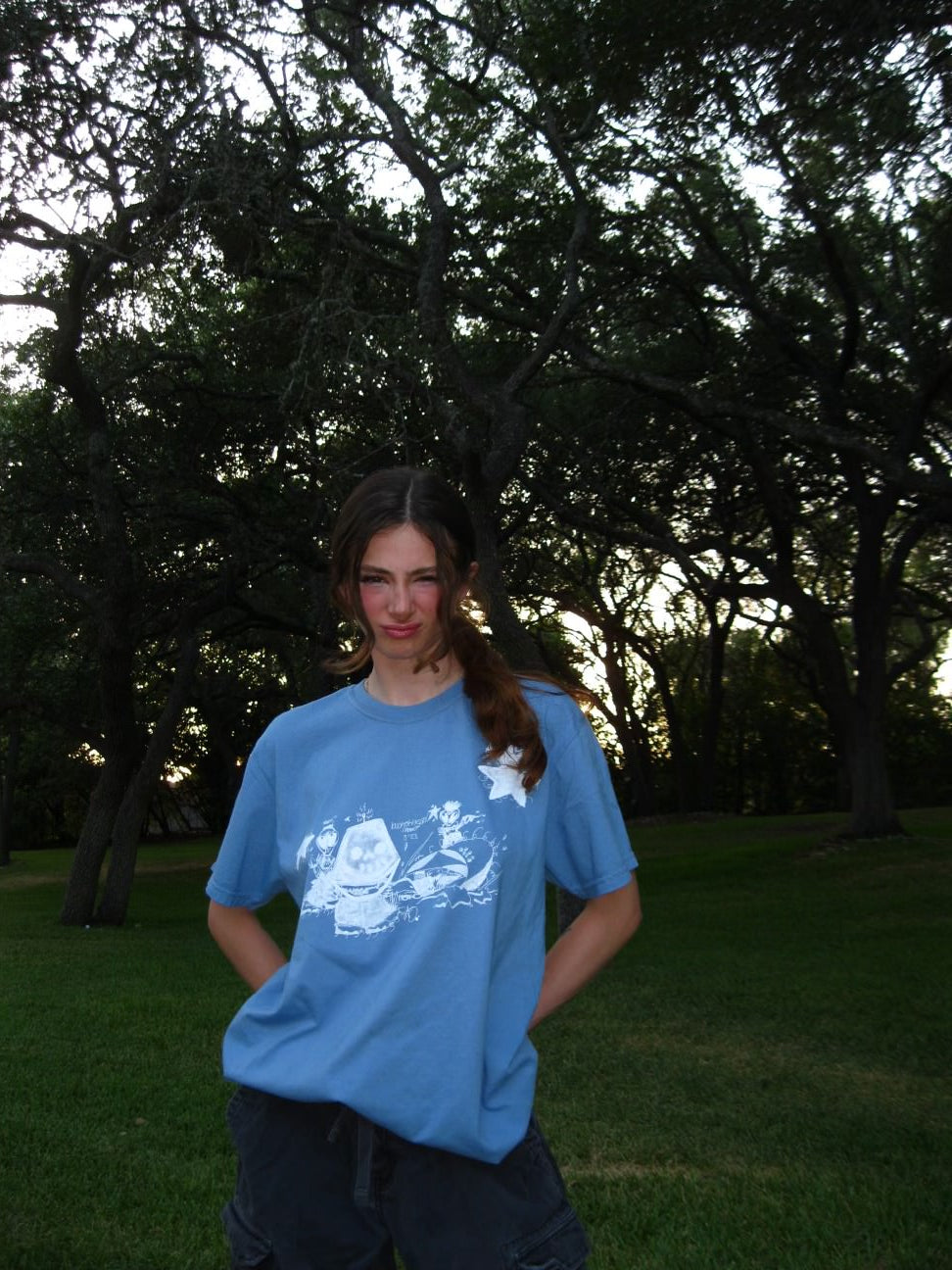 Person wearing a blue t-shirt with a white design outdoors
