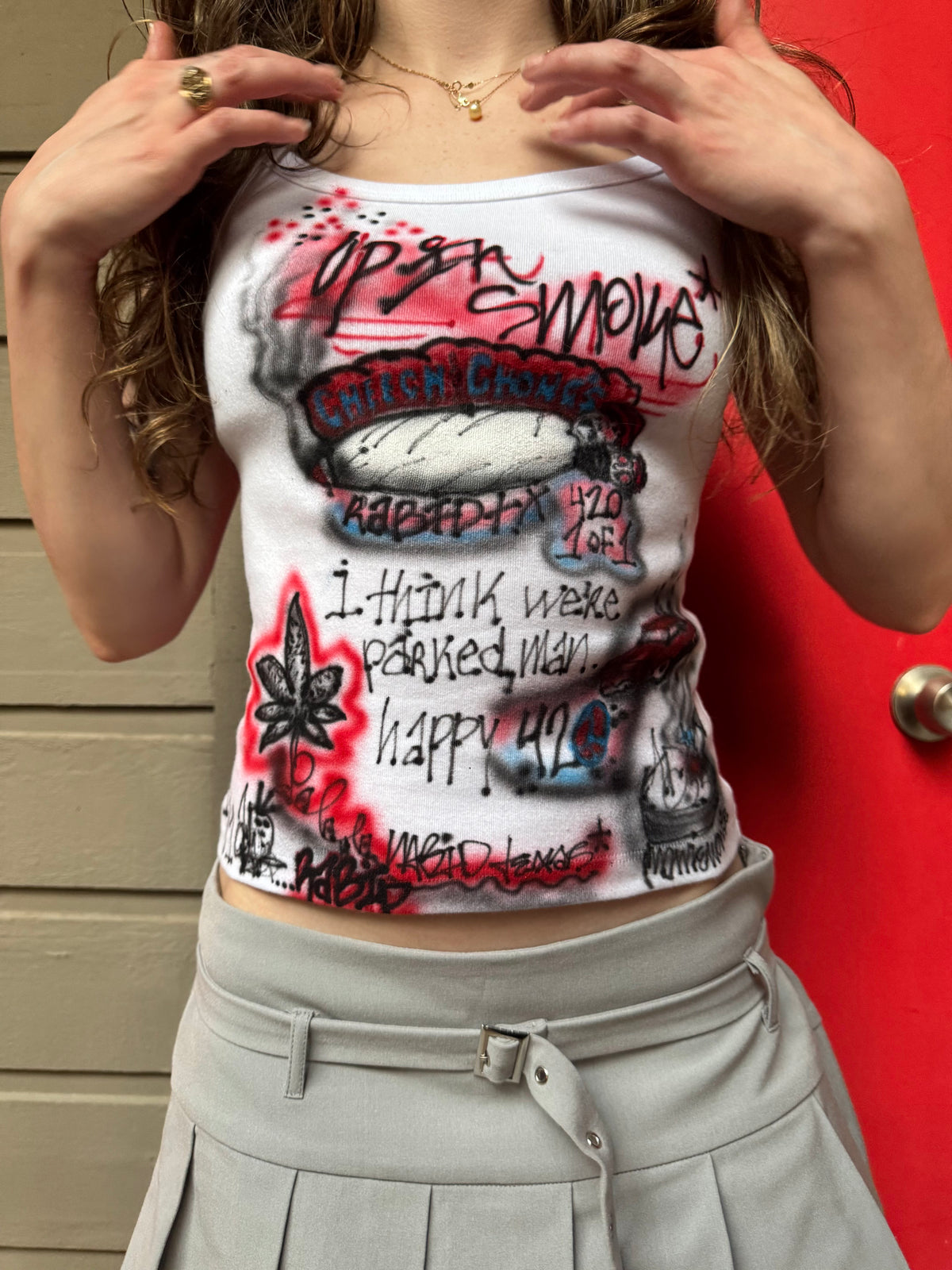 Person wearing a tank top with graphic designs and text against a red background