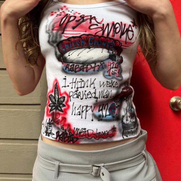Person wearing a tank top with graphic designs and text against a red background