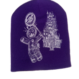 Embroidered beanie with a gingerbread man and castle design on a purple background